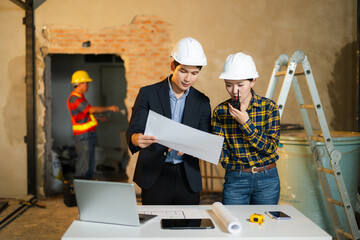 Team of engineers and architects in hard hats reviewing blueprints and planning a construction project. Concept of teamwork, design, innovation