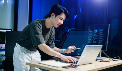 Programmer using stylus and laptop to write code at night. Coding workspace with tablet, monitor, and dark theme