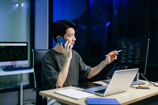 Asian software developer working late with code on screens, tablet, and phone. Concept of programming, tech lifestyle,