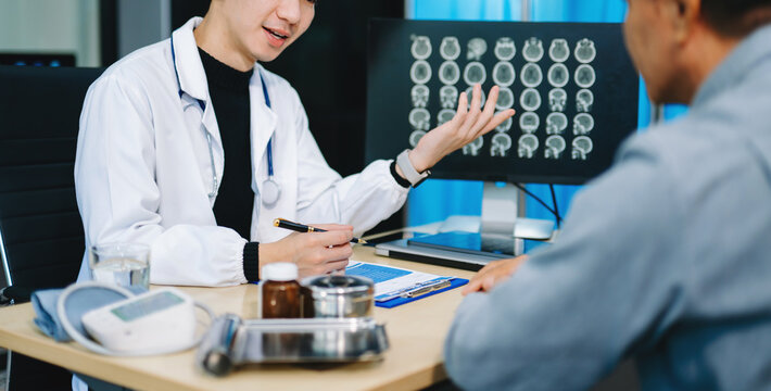 Doctor discusses brain scan results with patient using screen and clipboard. health care, neurology, diagnosis