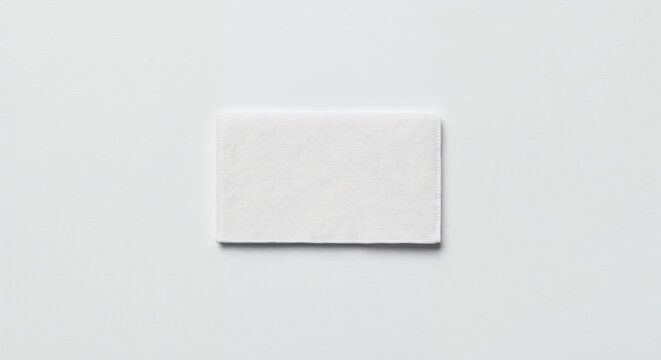 Care label patch isolated on white background, blank fabric tag, photorealistic top-down view