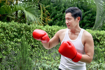 Muscular Asian man wears boxing gloves, punch in the air to exercise. Fitness strong man