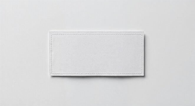 Care label patch isolated on white background, blank fabric tag, photorealistic top-down view