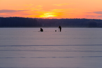 Silhouettes of People Making Ice Holes on Frozen Lake at Dawn — Winter Scene with Copy Space 