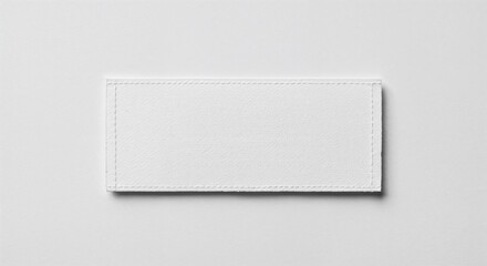 Care label patch isolated on white background, blank fabric tag, photorealistic top-down view