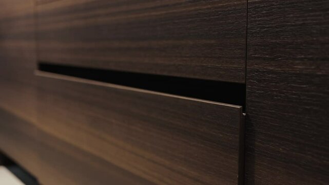 Close-up, female hand closing drawers of dark modern kitchen cabinets and showing dishes inside. Kitchen island, modern kitchen interior design.