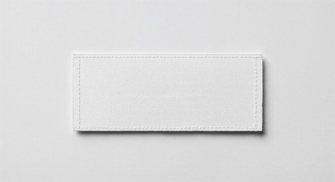 Care label patch isolated on white background, blank fabric tag, photorealistic top-down view