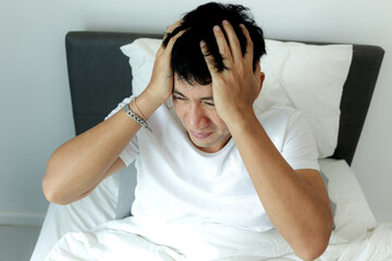 Asian man wakes up in the morning in his bedroom. A man sleeping on comfortable bed and trying to...
