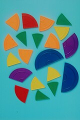 Violet orange yellow pieces of fractions on a table. Close up math material for study. Back to school, geometry lessons, mathematical education for preschooler. Creative study. background with numbers