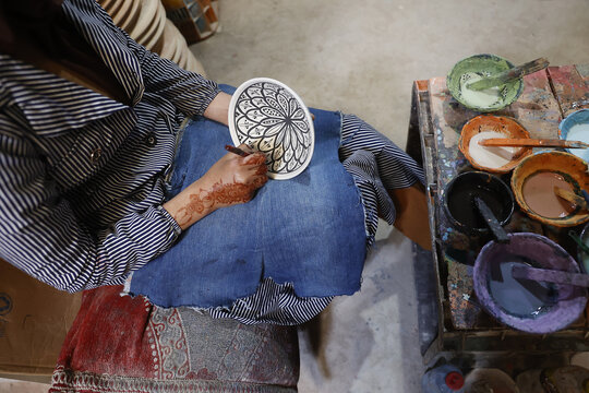 Worker painting bowls in a pottery workshop, Safi, Morocco