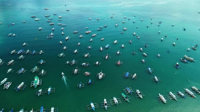 Drone top-down shot of dozens of colorful boats moored in the clear blue waters of El Nido, Palawan, Philippines. Traditional outrigger boats are lined up for island tours and fishing trips.