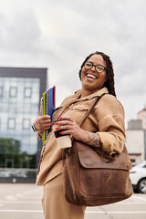 University teacher smiling confidently outside with books and coffee at campus in autumn