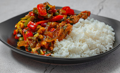 Asian style rice with meat on a black plate isolated