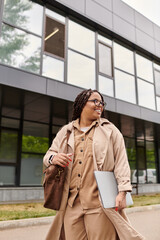 University teacher enjoys a sunny day while heading to class with her laptop and bag
