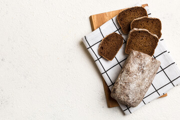 Freshly baked bread slices on cutting board against white wooden background. top view Sliced bread