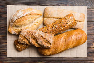 Assortment of freshly baked bread with napkin on rustic table top view. Healthy unleavened bread. French bread