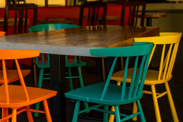 Colorful chairs surround a rustic table in a vibrant cafe setting during midday