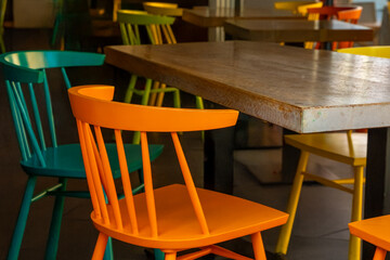 Colorful chairs surround a rustic table in a vibrant cafe setting during the golden hour
