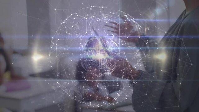 Teacher tapping tablet and gesturing animating hologram globe in class while student writing notes
