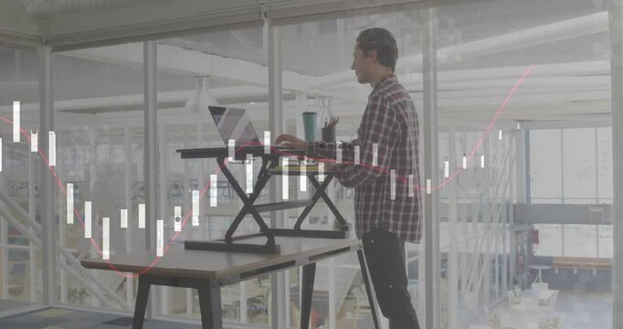 Man placing tumbler and pens at desk raising laptop riser typing data via finance chart overlay