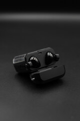 Black TWS earphones open with black background