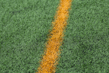 Close-up of a soccer field with green turf and orange lines