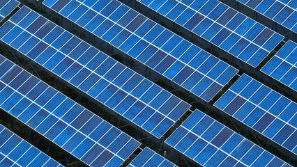 Drone shot revealing rows of blue solar panels arranged systematically, harnessing solar energy to reduce carbon footprint and promote eco-friendly electricity generation.
