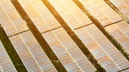 Aerial perspective of a solar farm with panels reflecting sunset hues, emphasizing renewable energy...