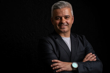 Smiling mature businessman in artistic chiaroscuro lighting on black background portrait