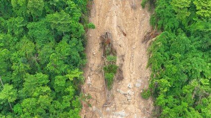 High-angle view of a landslide area affected by extreme weather, with mud, rocks, and debris...