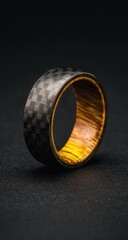 Fototapeta premium Wide carbon fiber and olive wood ring, angled on dark background, showcasing contrasting textures
