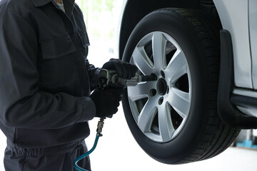 Mechanic changing tire at car service, closeup
