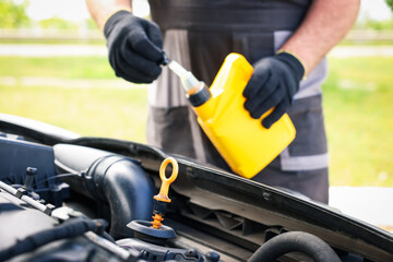 Worker checking motor oil level in car with dipstick, closeup