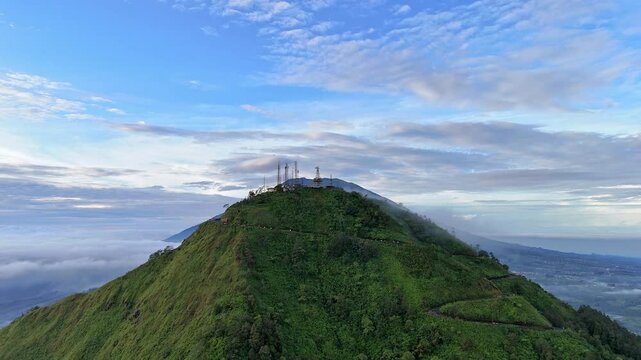 Drone fly rising up show the scenery the peak of Telomoyo Mountain with Merbabu Mountain background, Indonesia rural landscape.