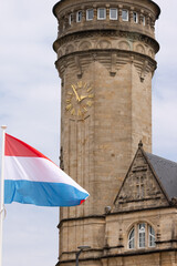 Luxembourg flag waving in front of historic clock tower building
