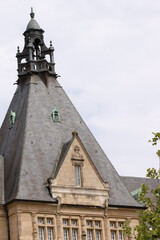 Historic European building with pointed roof framed by green trees
