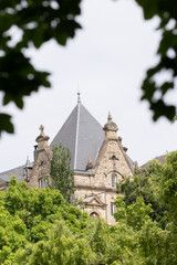Historic European building with pointed roof framed by green trees
