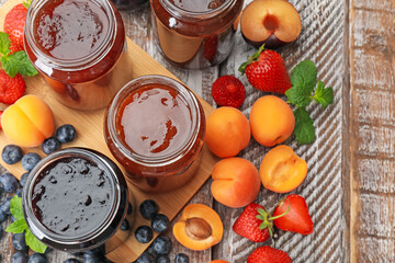 Different jams in jars and ingredients on wooden table, flat lay