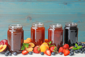 Different jams in jars and ingredients on white table. Space for text