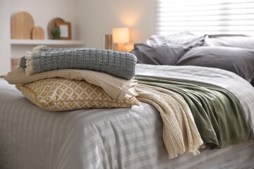 Comfortable bed with soft linens and blankets in room, closeup. Home textile