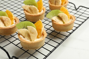 Tartlets with fruits on white marble table, closeup. Delicious dessert