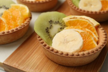 Tartlets with fruits on table, closeup. Delicious dessert