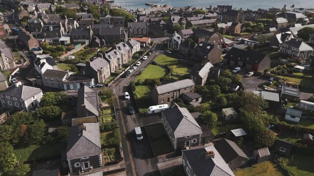 A sweeping up aerial drone shot of the harbour town of Lerwick, Shetland in Scotland, with buildings in the Bressay Sound.
