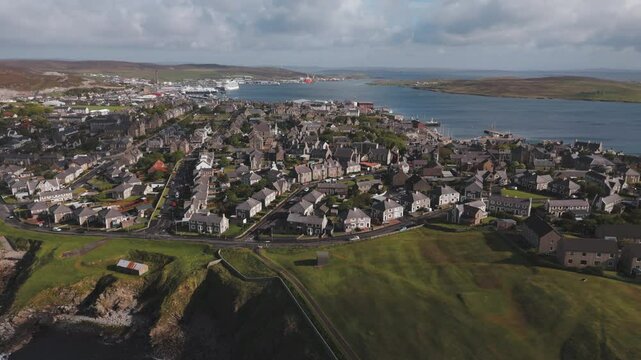 An aerial shot of the harbour town of Lerwick, Shetland in Scotland, with the blue water coastline.