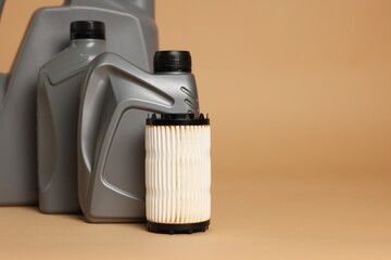 Motor oil in plastic canisters and filter on beige background, closeup. Space for text