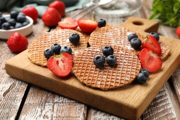 Tasty Dutch waffles (stroopwafels) and berries on wooden table, closeup