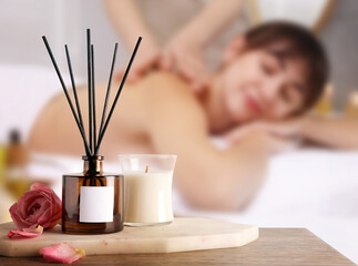 Spa therapy. Woman receiving massage on table and composition with aromatic reed air freshener in...