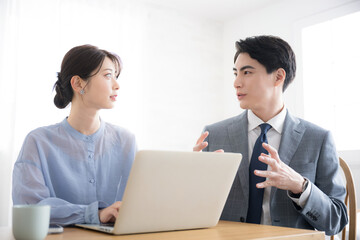 Fototapeta premium オフィスでパソコンを見るスーツを着たビジネスマン男女