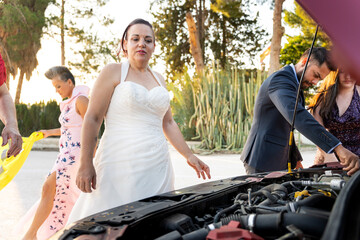 Bride and guests fixing broken down car on wedding day