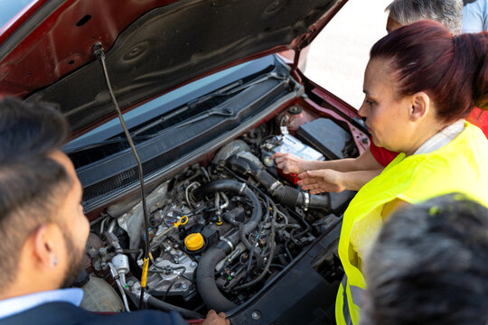 Mechanic woman explaining car engine problem to businessman